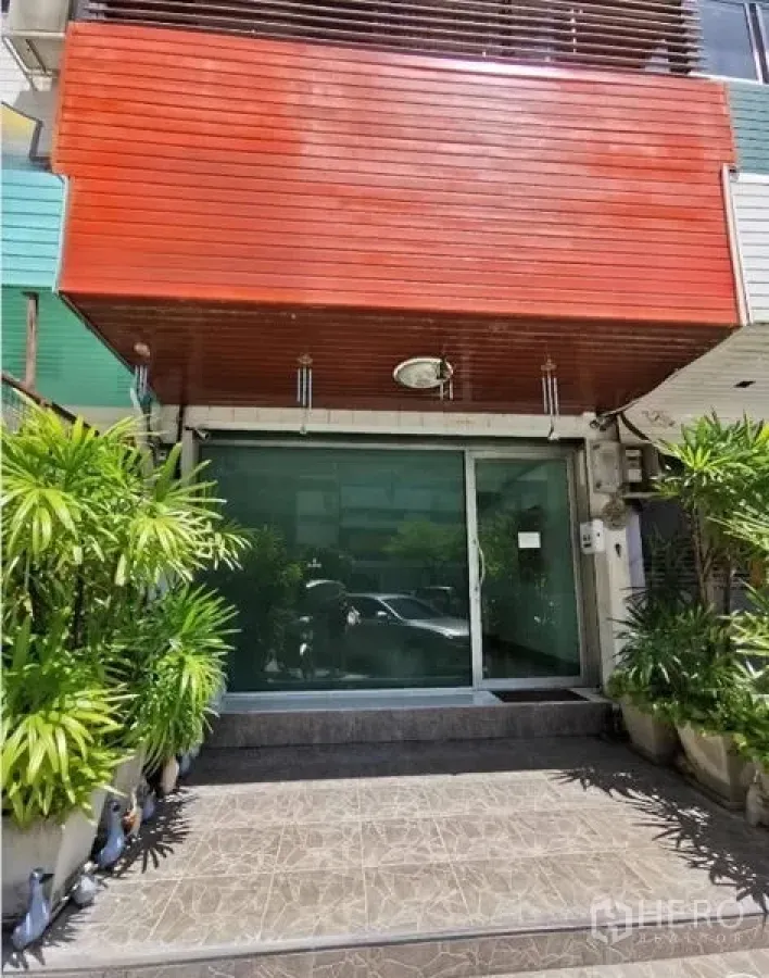 สำนักงาน ให้เช่าในHuai Khwang, Bangkok - ด้านหน้าอาคารพาณิชย์โลว์ไรส์ ประตูกระจกบานเลื่อน และทางขึ้นล้อมด้วยต้นไม้กระถาง.