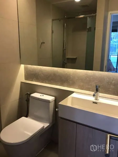 คอนโด ให้เช่าในKhlong Toei, Bangkok - ห้องน้ำโทนสีอ่อน อ่างล้างหน้า กระจกยาว โถสุขภัณฑ์ และฝักบัวแบบกระจกกั้น