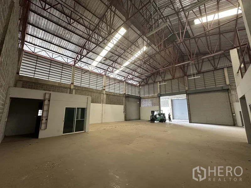 货栈 出租在Khlong Sam Wa, Bangkok - 仓库内部挑高空间，钢结构屋架与采光带，多个卷闸门，近口有叉车