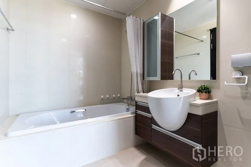 Condominium for rent - Modern bathroom featuring a built-in bathtub, wall-mounted vanity and large mirror.