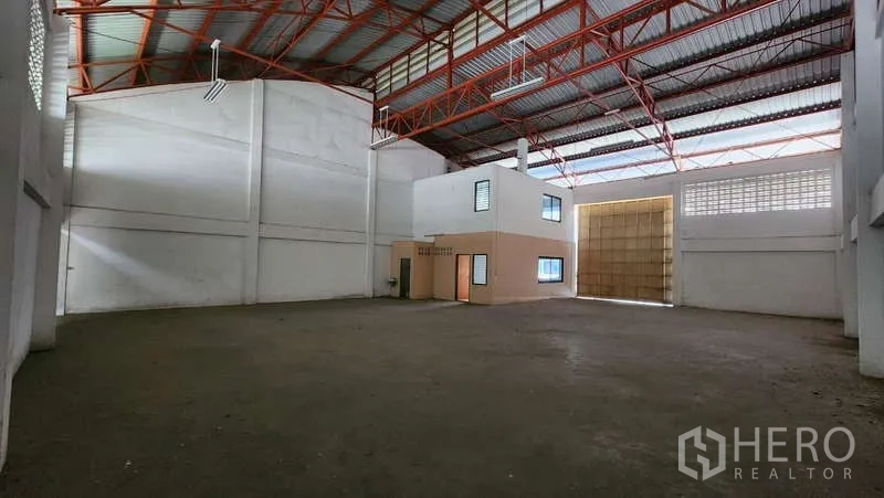 Warehouse for rent in Nong Khaem, Bangkok - Spacious warehouse interior with high red steel truss roof, large sliding loading door, and mezzanine office block.