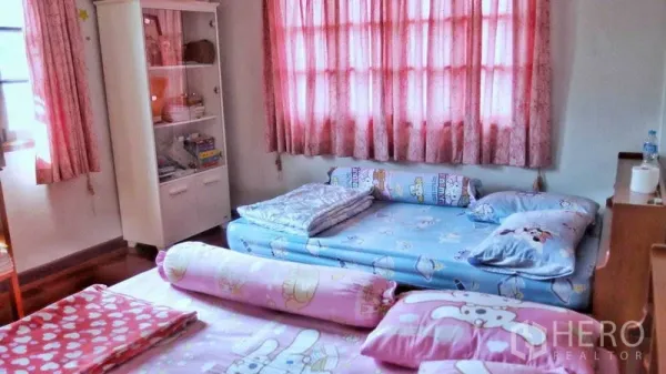 Detached House for sale in Taling Chan, Bangkok - Cozy bedroom with floor mattresses, pink curtains and a tall white cabinet.