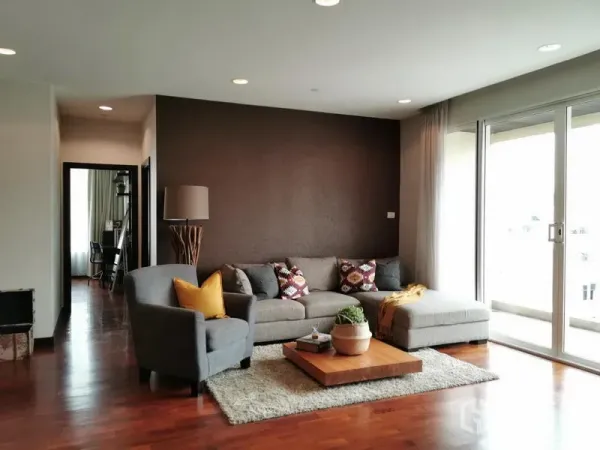 คอนโด ให้เช่าหรือขายในKhlong Toei, Bangkok - ห้องนั่งเล่นสว่างพร้อมโซฟาเข้ามุมสีเทา พื้นไม้ โต๊ะกลาง และประตูกระจกบานเลื่อนออกสู่ระเบียง