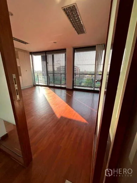 Home Office for rent or sale in Bang Phli, Samut Prakan - Bright corner office with floor-to-ceiling windows and sunset light across wood flooring.