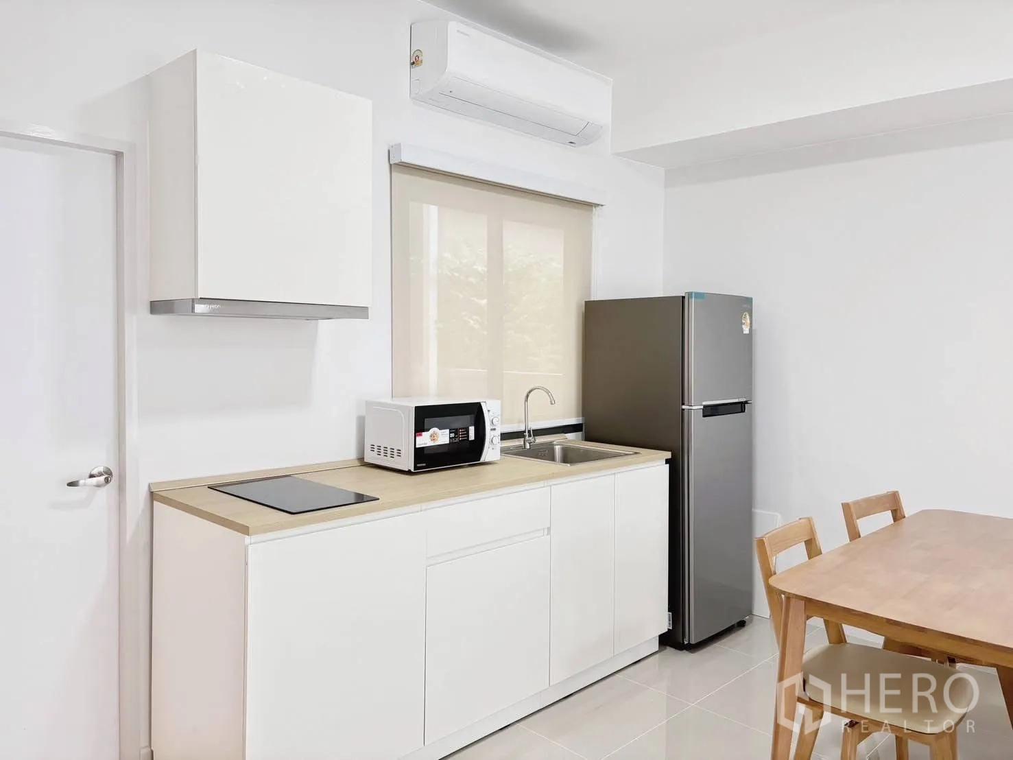 ทาวน์เฮาส์ for rent in Bang Phli, Samut Prakan - ครัวสีขาวขนาดกะทัดรัด มีเตาไฟฟ้า ไมโครเวฟ อ่างล้างจาน และตู้เย็นข้างชุดทานข้าว.