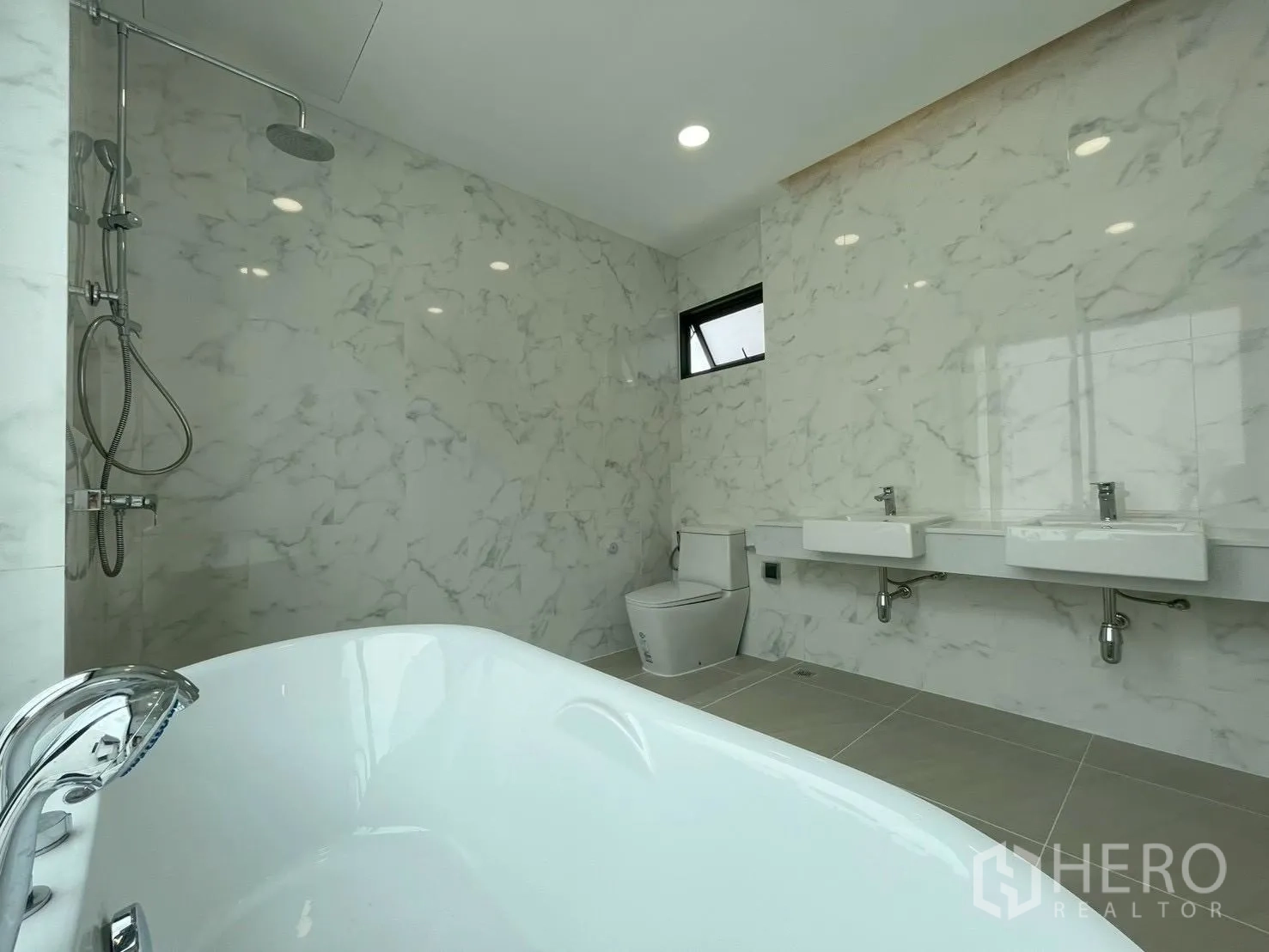 Detached House for sale in Chatuchak, Bangkok - Marble-tiled bathroom with freestanding bathtub, rain shower, double sinks, and toilet.