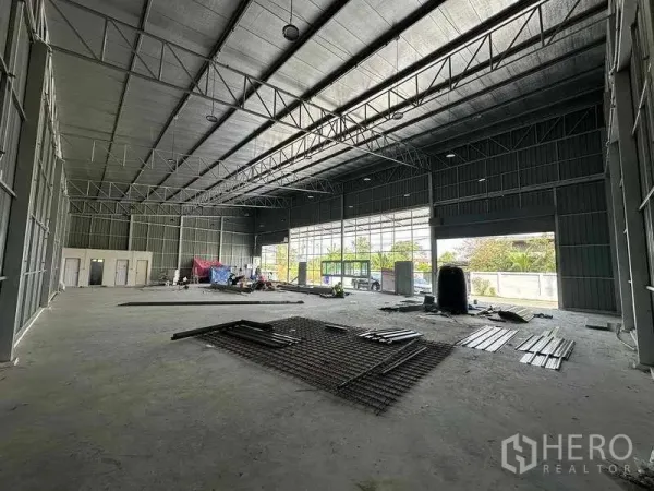 Warehouse for rent in Pak Kret, Nonthaburi - Open-plan storage area with full-height glazing, large roller doors and natural light across the concrete floor.