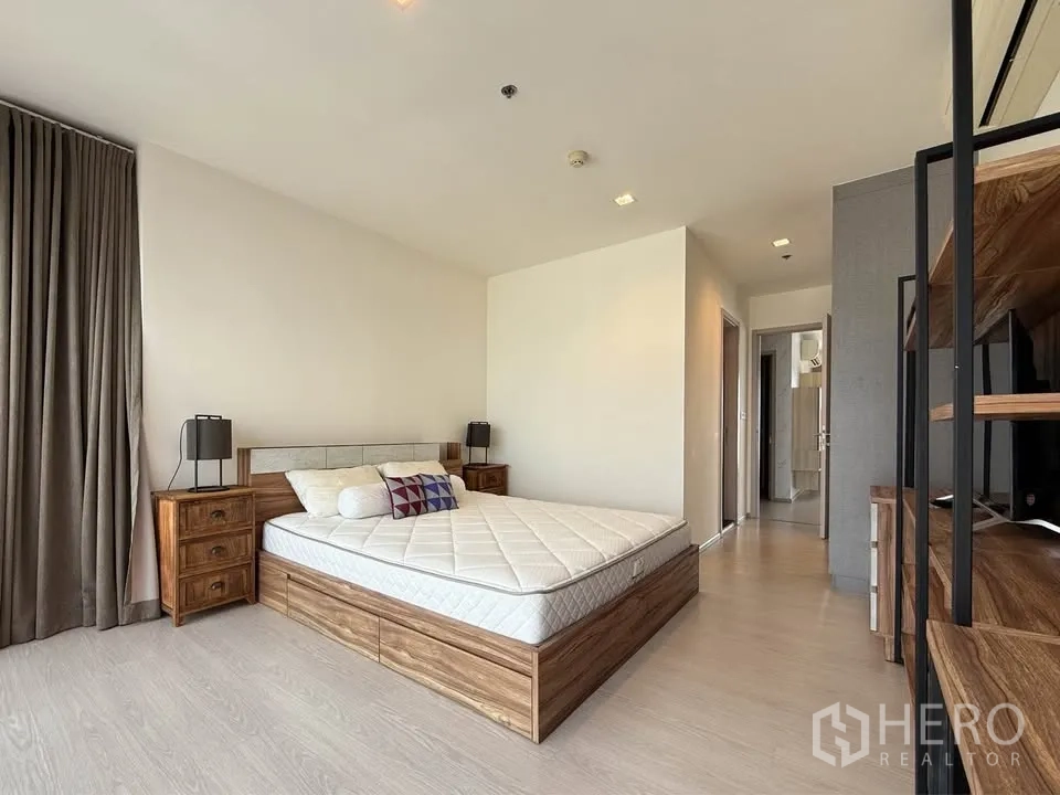 Condominium for rent in Khlong Toei, Bangkok - Room with wooden bed, corridor view and neutral décor.