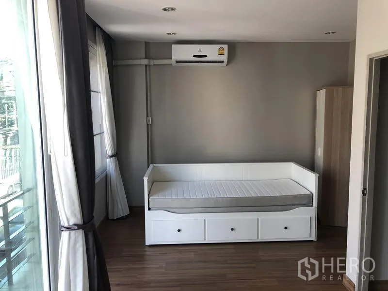 ทาวน์เฮาส์ ให้เช่าในYan Nawa, Bangkok - ห้องนอนสว่าง เตียงเดย์เบด พื้นไม้ ประตูออกระเบียง และเครื่องปรับอากาศ