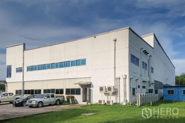 工厂 出售在Rayong - 连接式办公楼，蓝色窗带、外机组与地面停车。