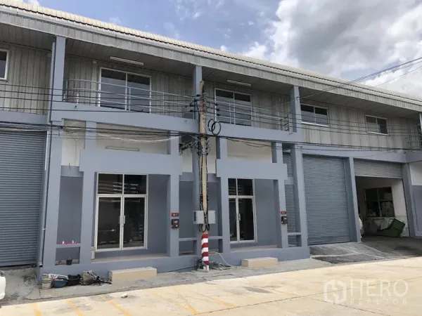 Factory for rent in Pak Kret, Nonthaburi - Row of adjoining factory units with upper balconies and large loading doors.