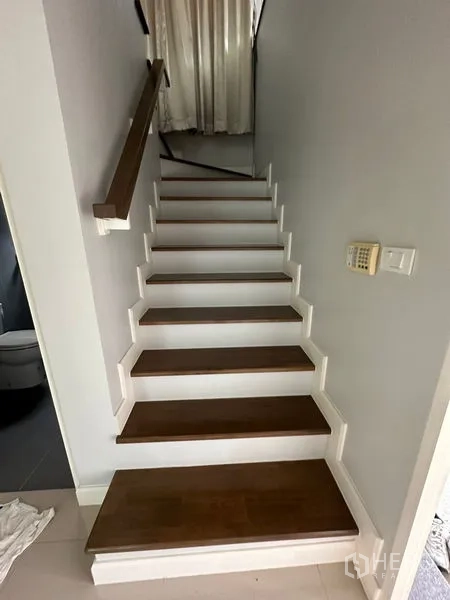 บ้าน ให้เช่าหรือขายในLam Luk Ka, Pathum Thani - บันไดพื้นไม้ ราวสีขาว พร้อมแผงควบคุมความปลอดภัยที่ผนัง