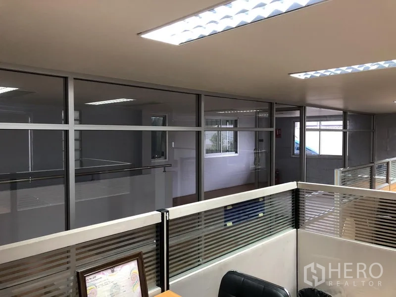 Factory for sale in Pathum Thani - Office cubicles with glass walls overlooking the hallway.