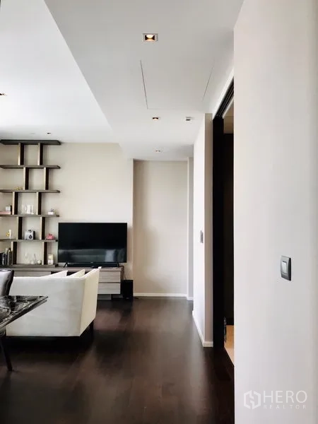 คอนโด ให้เช่าหรือขายในWatthana, Bangkok - มุมมองห้องนั่งเล่นสมัยใหม่ ชั้นวางตกแต่ง ทีวี และหน้าต่างบานใหญ่ข้างโต๊ะอาหาร