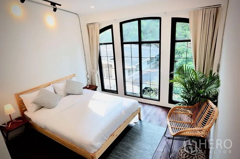 ทาวน์เฮาส์ ให้เช่าในSathon, Bangkok - ห้องนอนสว่าง หน้าต่างโค้งกรอบอลูมิเนียมสีดำ เตียงไม้และเก้าอี้หวาย