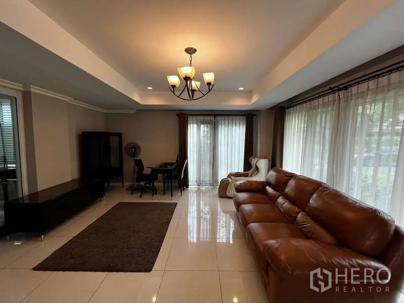 บ้าน ให้เช่าในPrawet, Bangkok - ห้องนั่งเล่นมีโซฟาหนัง โคมแชนเดอเลียร์ และม่านโปร่ง.