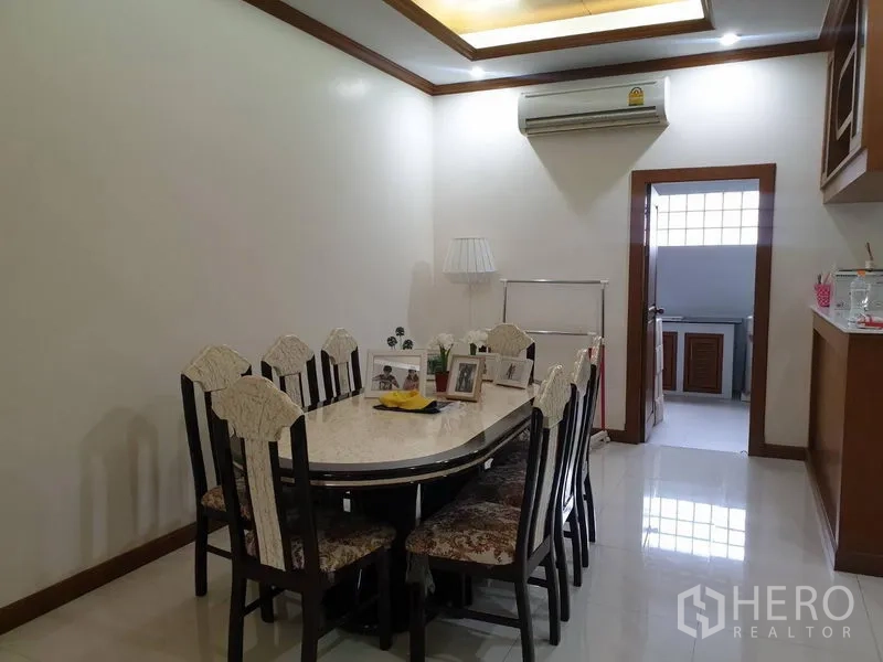 Townhouse for rent in Bang Kho Laem, Bangkok - Bright dining room with an eight-seat marble-top table, recessed ceiling and doorway to a fitted kitchen.