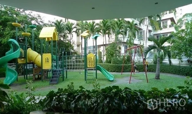 คอนโด ให้เช่าในWatthana, Bangkok - สนามเด็กเล่นท่ามกลางสวน มีสไลเดอร์ ชิงช้า และเครื่องเล่นปีนป่าย รายล้อมด้วยต้นปาล์ม