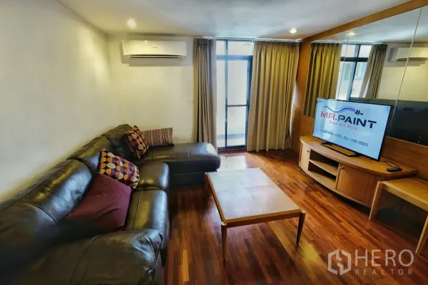 คอนโด ให้เช่าในWatthana, Bangkok - ห้องนั่งเล่น โซฟาหนังรูปตัวแอล โต๊ะกลาง และประตูกระจกออกสู่ระเบียง