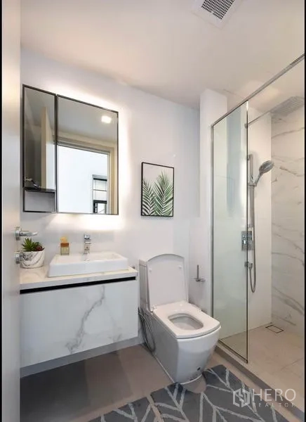 公寓 出租在Phra Khanong, Bangkok - 现代白色浴室，玻璃淋浴间与洗手台。