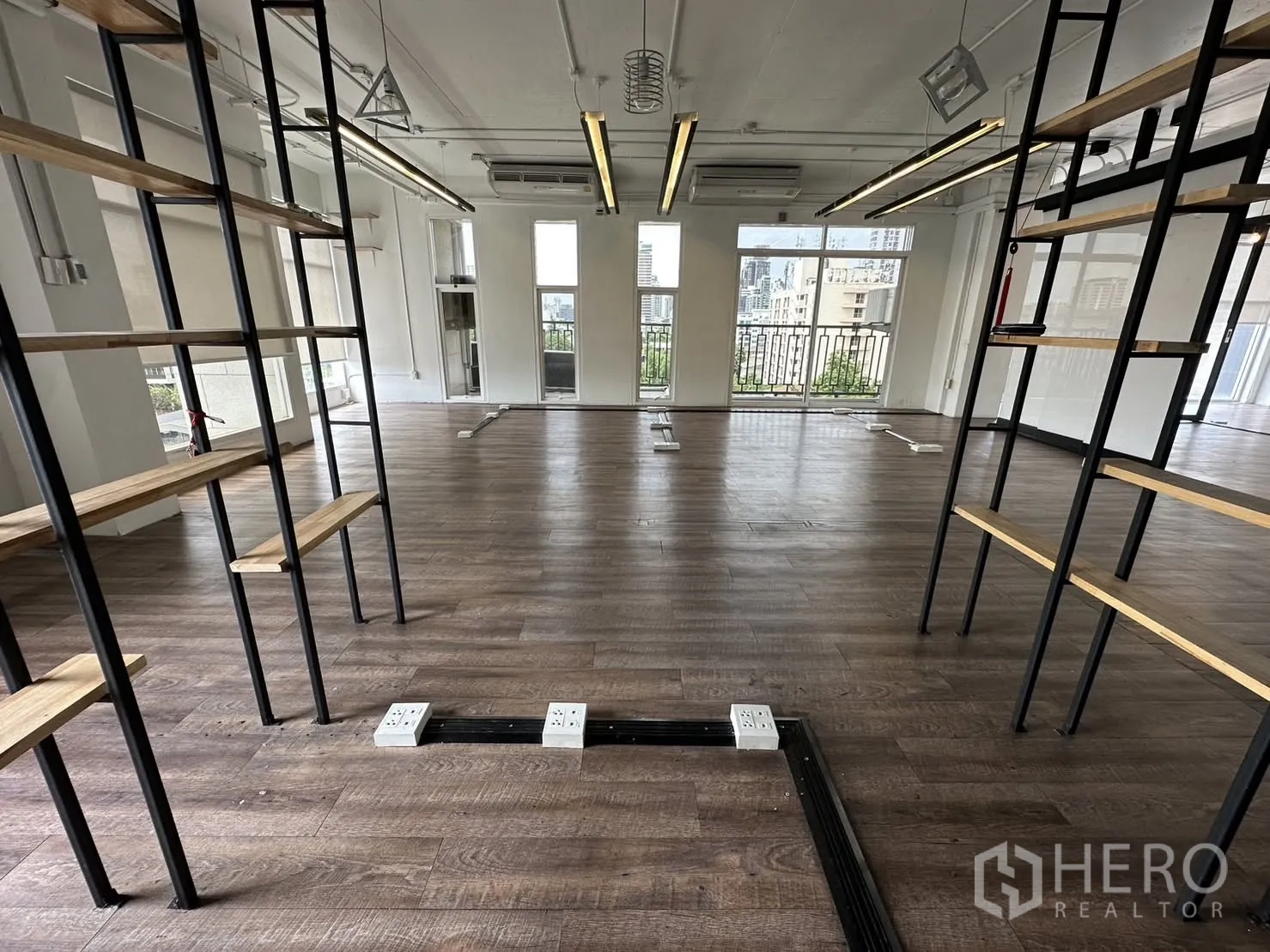 ออฟฟิศ for rent in Watthana, Bangkok - ออฟฟิศโถงกว้างพื้นลายไม้ หน้าต่างบานใหญ่ ราวระเบียง ไฟเส้น และชั้นวางเปิด พร้อมช่องปลั๊กไฟพื้น