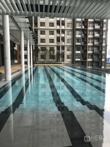 Condominium for rent in Huai Khwang, Bangkok - Condominium lap pool with shaded deck and city-facing facade