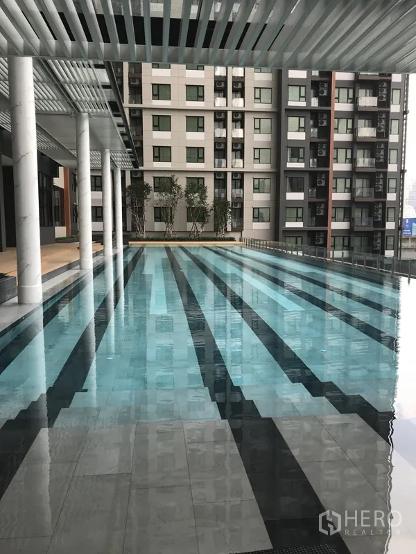 Condominium for rent in Huai Khwang, Bangkok - Condominium lap pool with shaded deck and city-facing facade