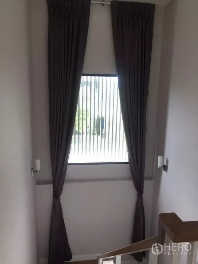Detached House for rent in Samut Prakan - Stair landing with tall window and full-length curtains providing natural light.
