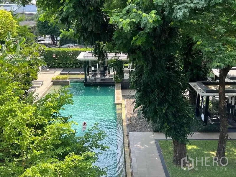 公寓 出售在Watthana, Bangkok - 绿荫环绕的室外泳池，设有躺椅与凉亭。