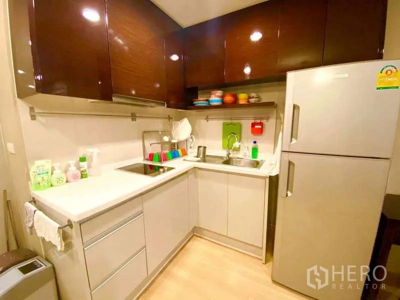 公寓 出租在Ratchathewi, Bangkok - U 型现代厨房，亮面橱柜、水槽、炉灶与大冰箱。