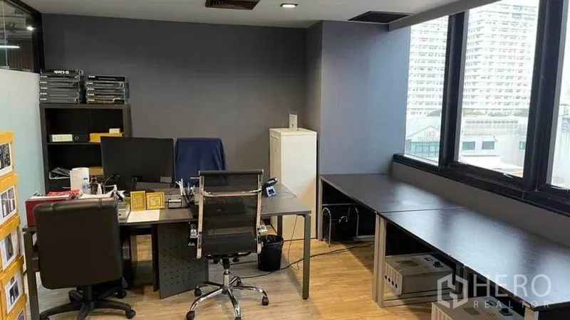 สำนักงาน ให้เช่าในKhlong Toei, Bangkok - มุมออฟฟิศติดหน้าต่างบานใหญ่ ผนังโทนเข้ม พร้อมโต๊ะและชั้นวาง