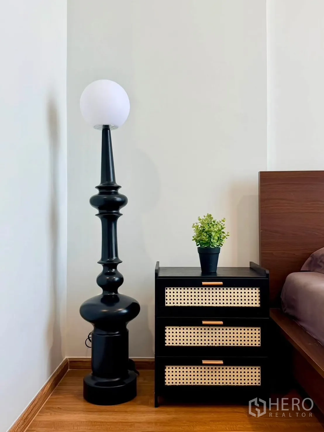 Townhouse for rent in Bang Phli, Samut Prakan - Bedside table with woven drawers next to a tall black floor lamp.