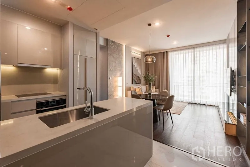 คอนโด ให้เช่าในWatthana, Bangkok - ครัวแบบเปิดพร้อมไอส์แลนด์สีขาวและอ่างล้างจาน เชื่อมต่อพื้นที่นั่งเล่น–รับประทานอาหารและผ้าม่านสูงจรดเพดาน