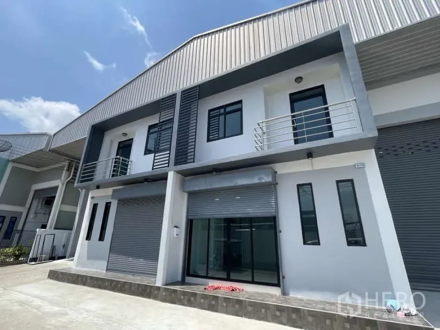 Factory for rent in Ban Phaeo, Samut Sakhon - Modern factory facade with two-storey office, balconies and roller shutters.