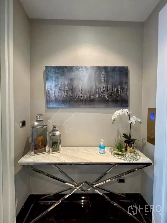 คอนโด ให้เช่าในWatthana, Bangkok - โถงทางเข้าตกแต่งด้วยโต๊ะคอนโซลหินอ่อน โคมไฟ และภาพเมือง