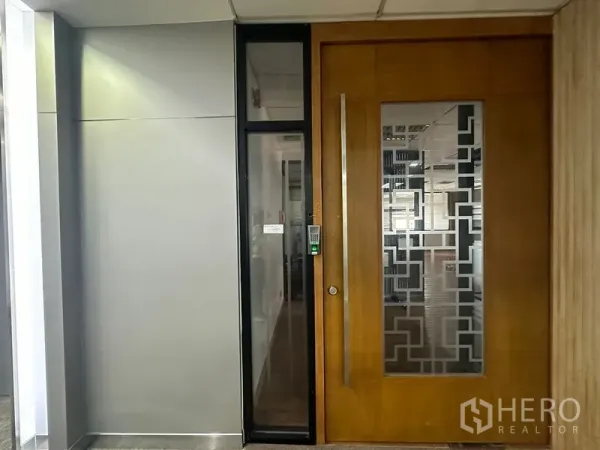 办公空间 出租在Bang Rak, Bangkok - 办公室门口特写，按键门禁与装饰磨砂玻璃，位于商业楼层走道。
