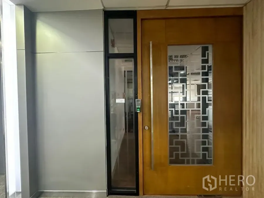 办公空间 出租在Bang Rak, Bangkok - 办公室门口特写，按键门禁与装饰磨砂玻璃，位于商业楼层走道。