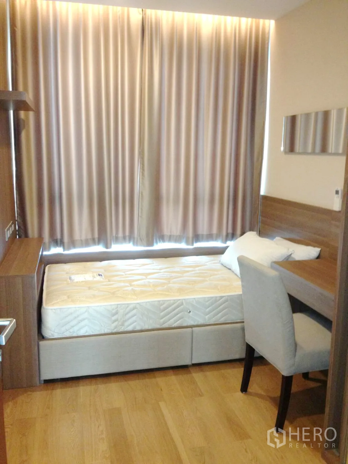 Condominium for rent in Ratchathewi, Bangkok - Second bedroom with single bed, work desk, built-in shelving and curtained window.