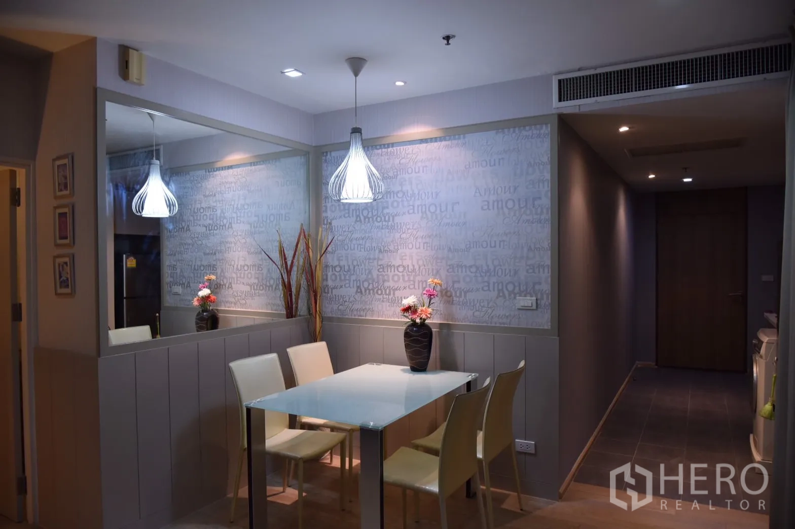Condominium for rent or sale in Khlong Toei, Bangkok - Cozy dining area with glass-top table, four chairs and pendant lights beside a mirrored wall.