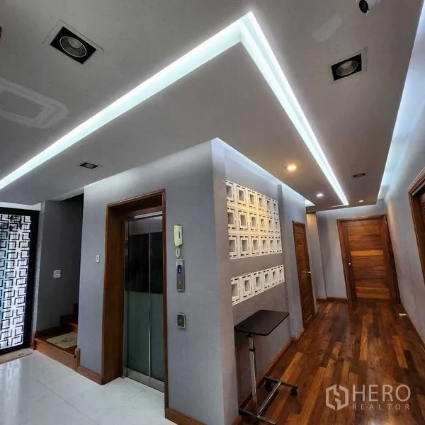 บ้าน ขายในPhra Khanong, Bangkok - โถงในบ้านมีลิฟต์ส่วนตัว ไฟเส้น LED และประตูไม้หลายบาน