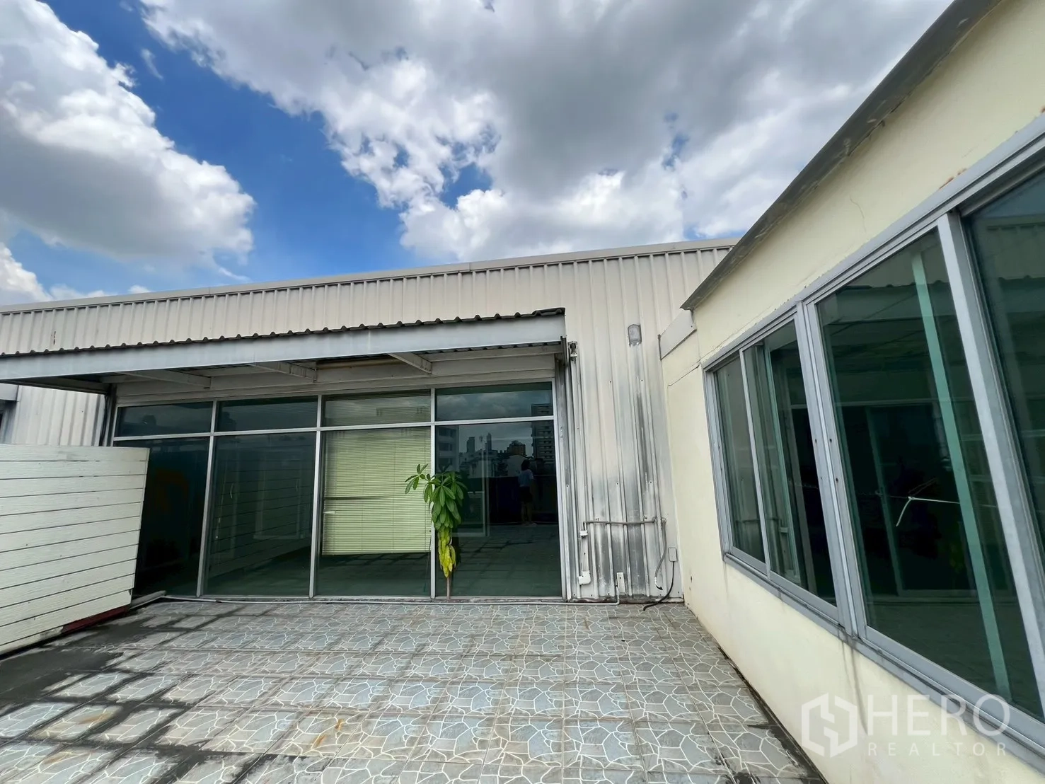 Shophouse for rent - Rooftop area adjoining glass-walled rooms and metal awning.