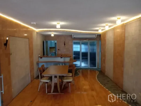 Condominium for rent in Pathum Wan, Bangkok - Dining area with wooden table, built-in bar counter and sliding glass doors.