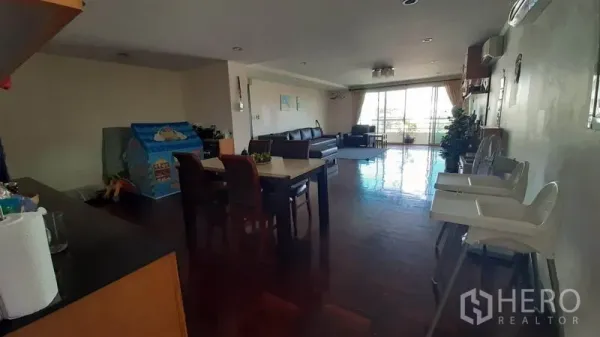 คอนโด ให้เช่าในWatthana, Bangkok - พื้นที่นั่งเล่นกว้าง พื้นไม้ โต๊ะทานอาหาร และประตูบานเลื่อนสู่ระเบียงที่สว่างปลายห้อง