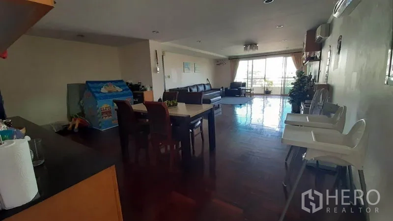 คอนโด ให้เช่าในWatthana, Bangkok - พื้นที่นั่งเล่นกว้าง พื้นไม้ โต๊ะทานอาหาร และประตูบานเลื่อนสู่ระเบียงที่สว่างปลายห้อง