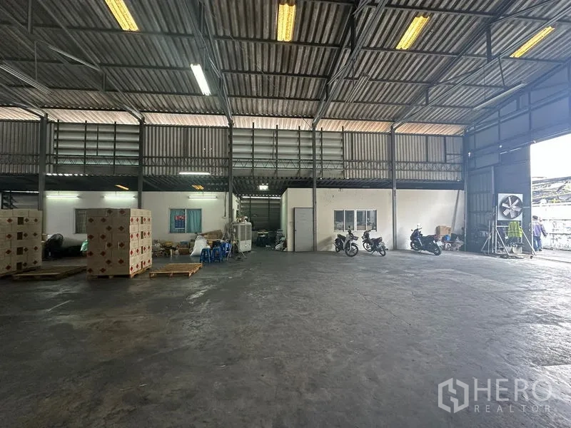 Warehouse for rent in Suan Luang, Bangkok - Open warehouse bay with high steel truss ceiling and fluorescent lighting.