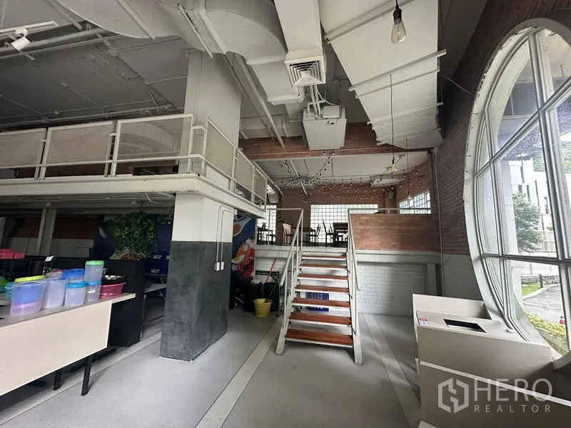 零售空间 出租在Watthana, Bangkok - 通往夹层的楼梯，旁有大型圆形窗。