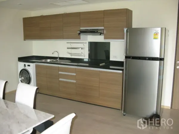 คอนโด ให้เช่าในKhlong Toei, Bangkok - ครัวแนวตรงสไตล์โมเดิร์น ตู้ลายไม้ ท็อปสีดำ เตา เครื่องดูดควัน ตู้เย็น และเครื่องซักผ้า