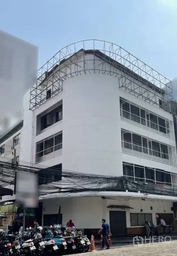 พื้นที่ขายปลีก ให้เช่าในBang Rak, Bangkok - อาคารพาณิชย์มุมตึกสีขาวสูงสี่ชั้น หน้าต่างกระจกบานกว้าง มีโครงเหล็กบนดาดฟ้า ชั้นล่างเป็นหน้าร้าน ใกล้ย่านสีลม