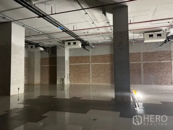 零售空间 出租 - 开放式零售毛坯区，砖纹墙面、结构立柱与亮面地砖清晰可见。