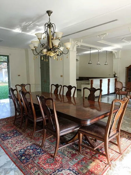 Detached House for rent or sale in Krathum Baen, Samut Sakhon - Formal dining room with long wooden table, chandelier and open kitchen bar.